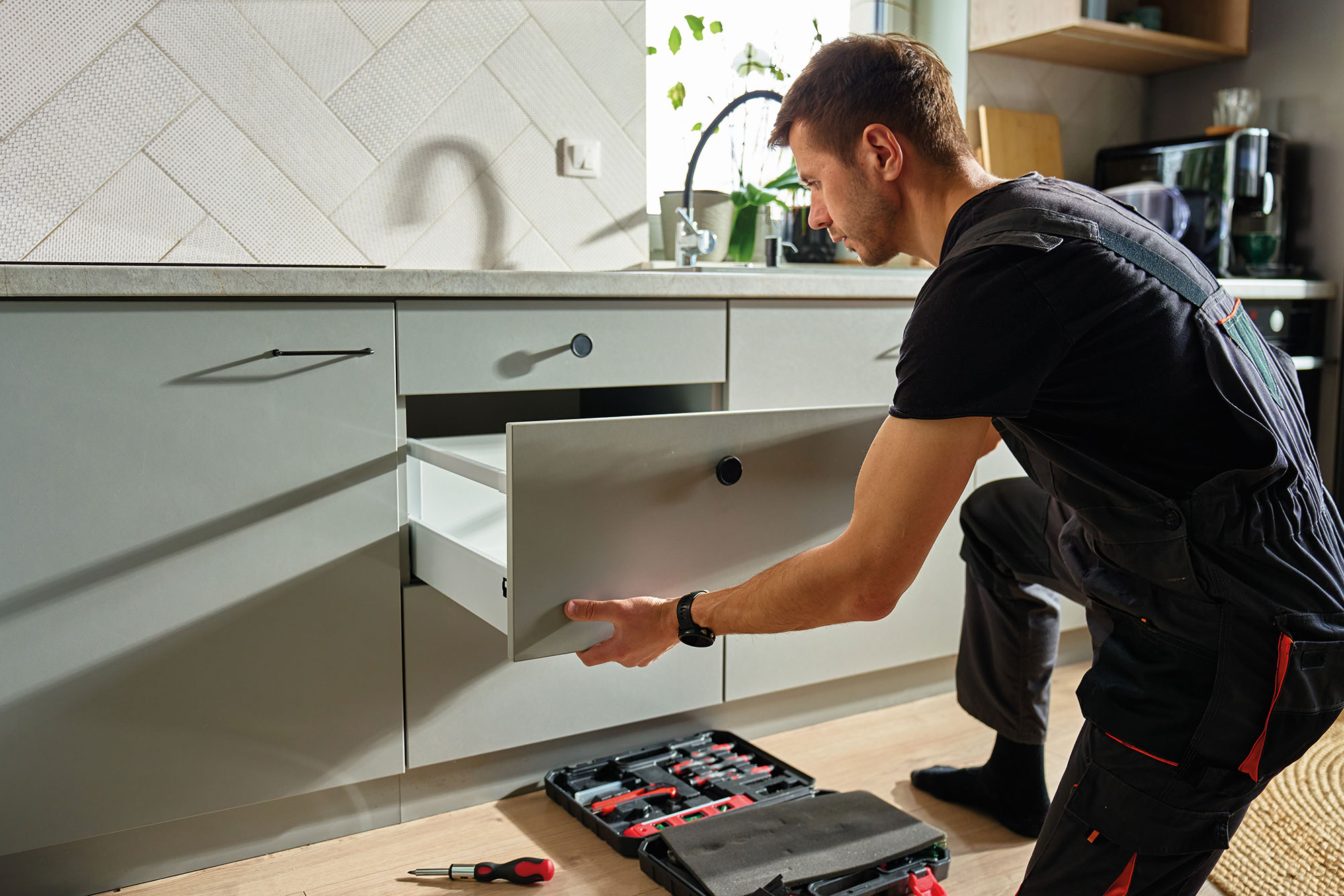 Modern kitchen worker installing cabinetry
